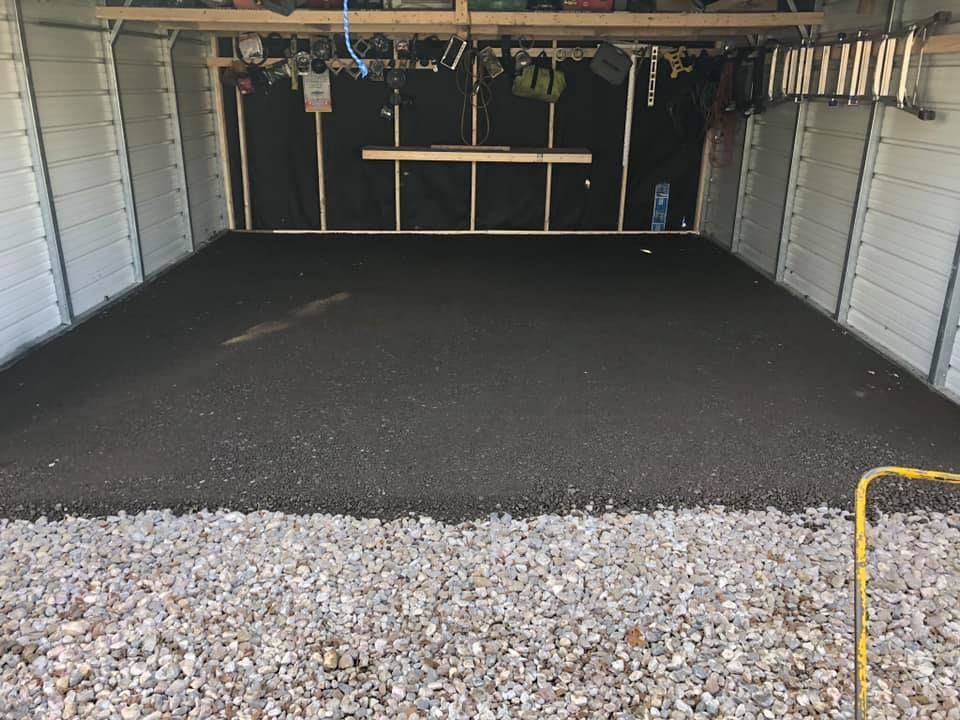 A garage with a gravel floor and a concrete floor.