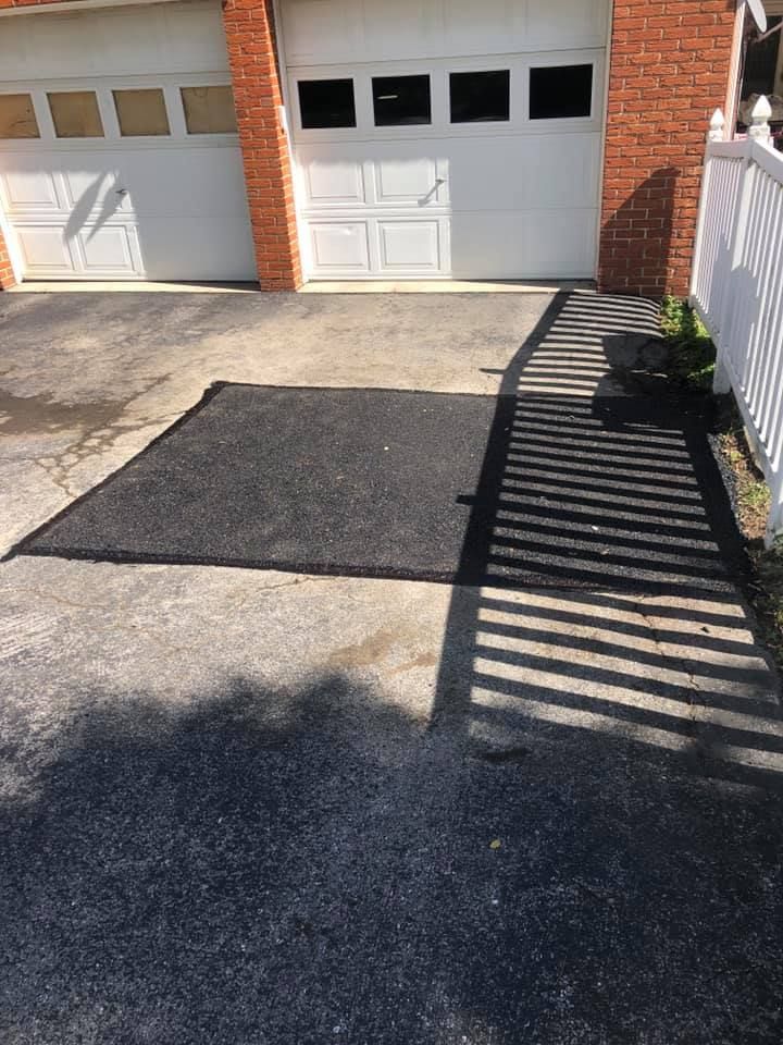 A driveway with a black mat in front of a garage door.