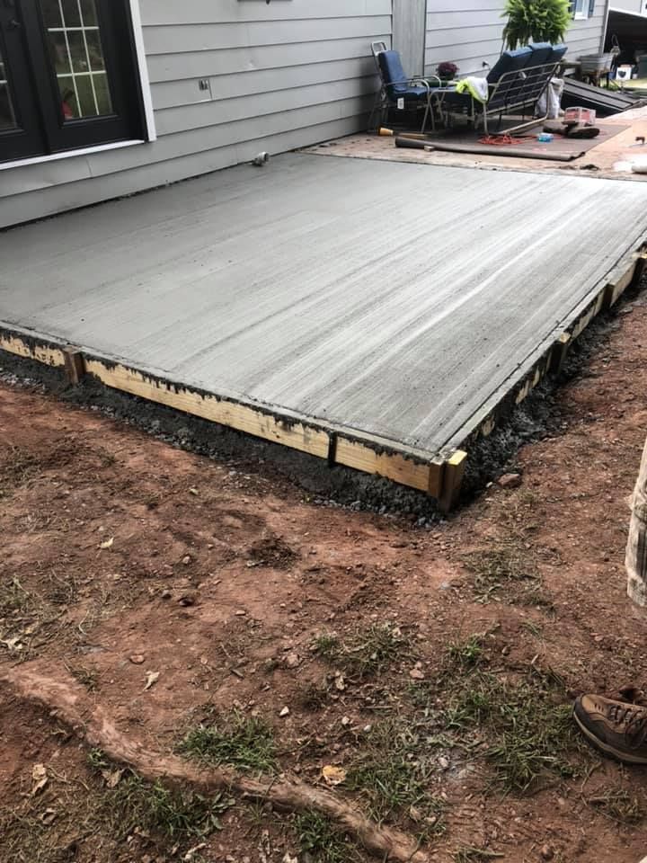 A concrete patio is being built in front of a house.