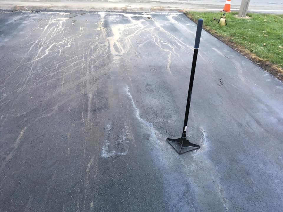 A shovel is sitting on the ground in a parking lot.