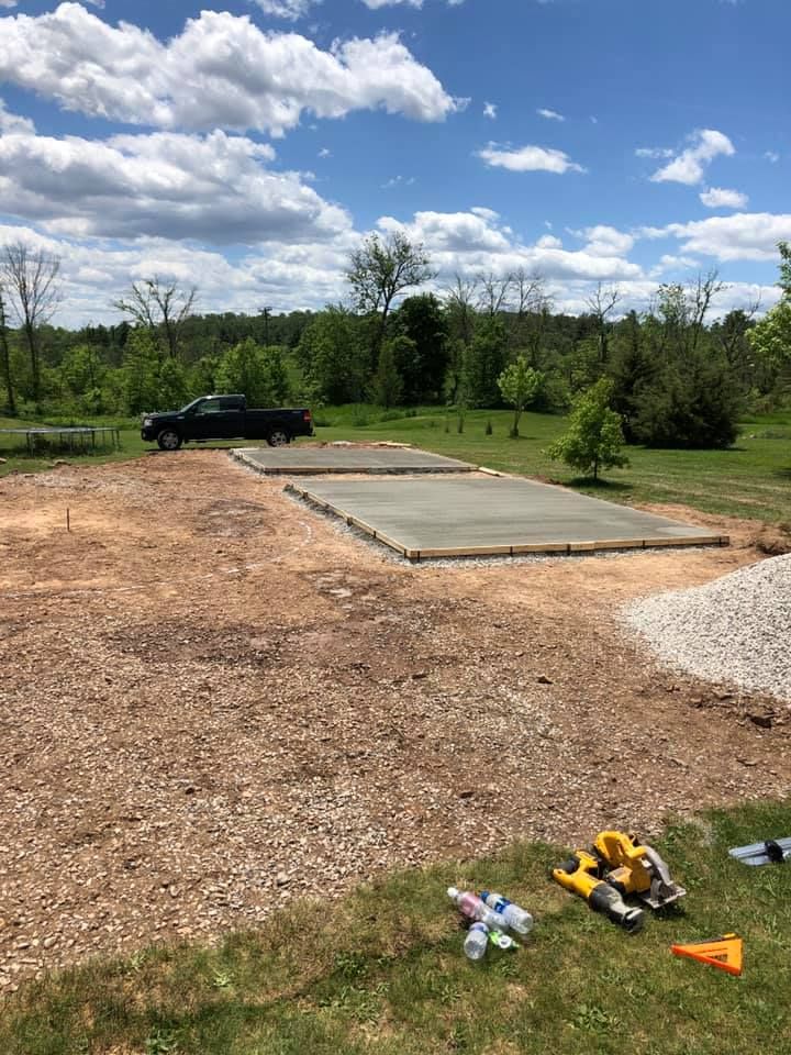 A truck is parked in a dirt lot next to a concrete slab.
