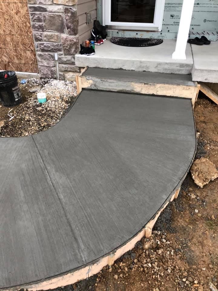A curved concrete walkway is being built in front of a house.