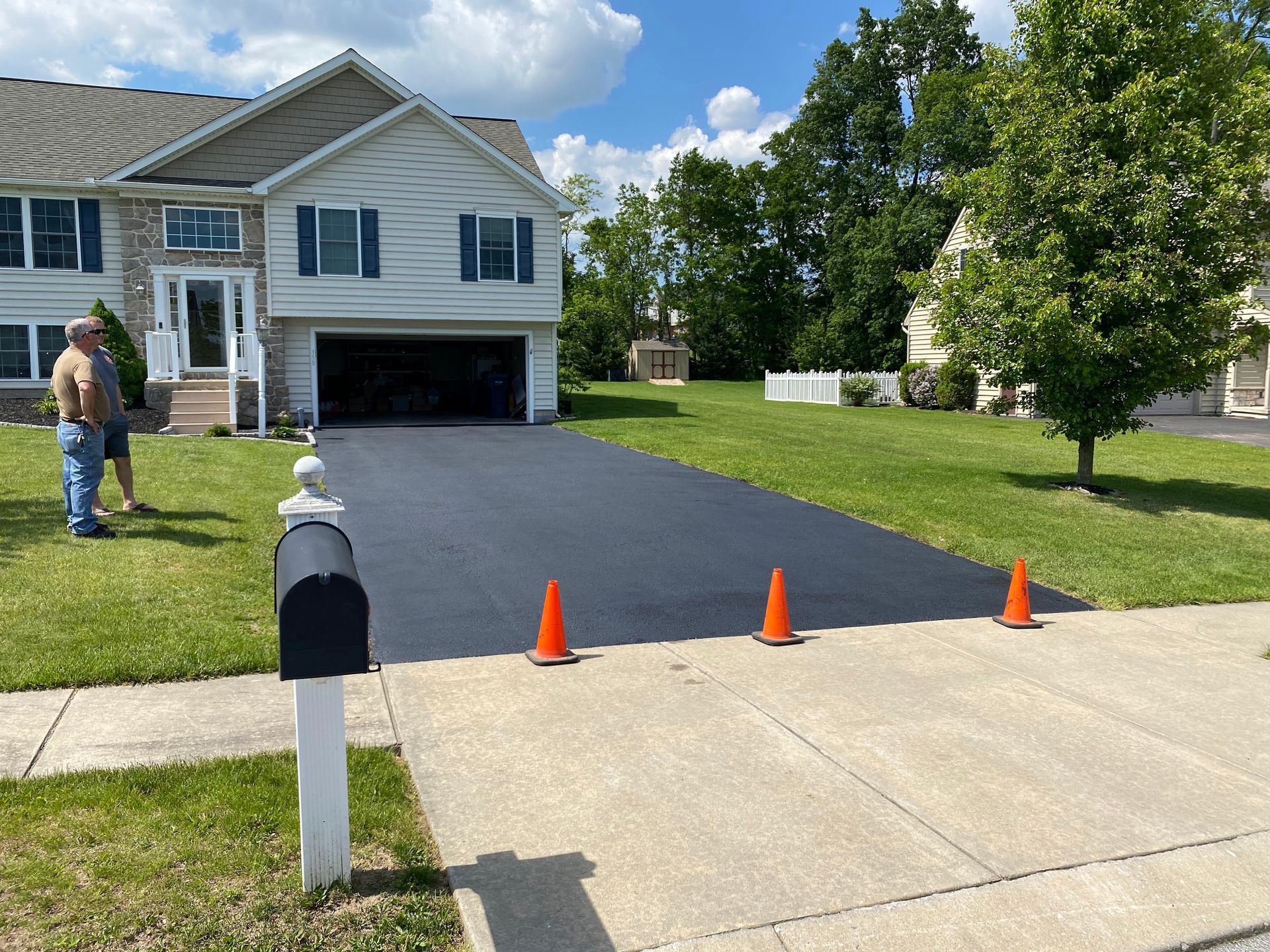 A man is standing next to a mailbox in front of a house.