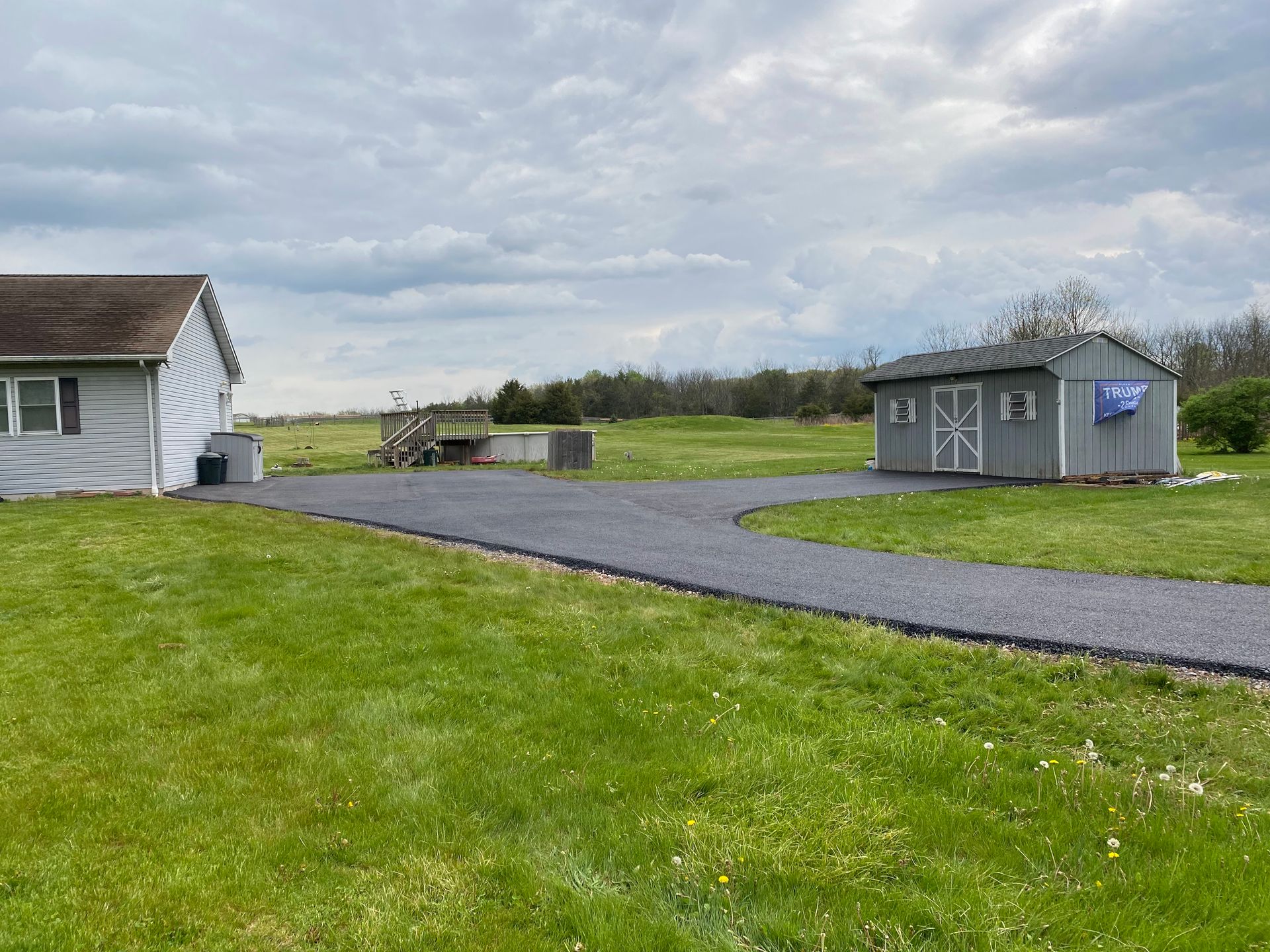A house and a shed are in the middle of a grassy field.