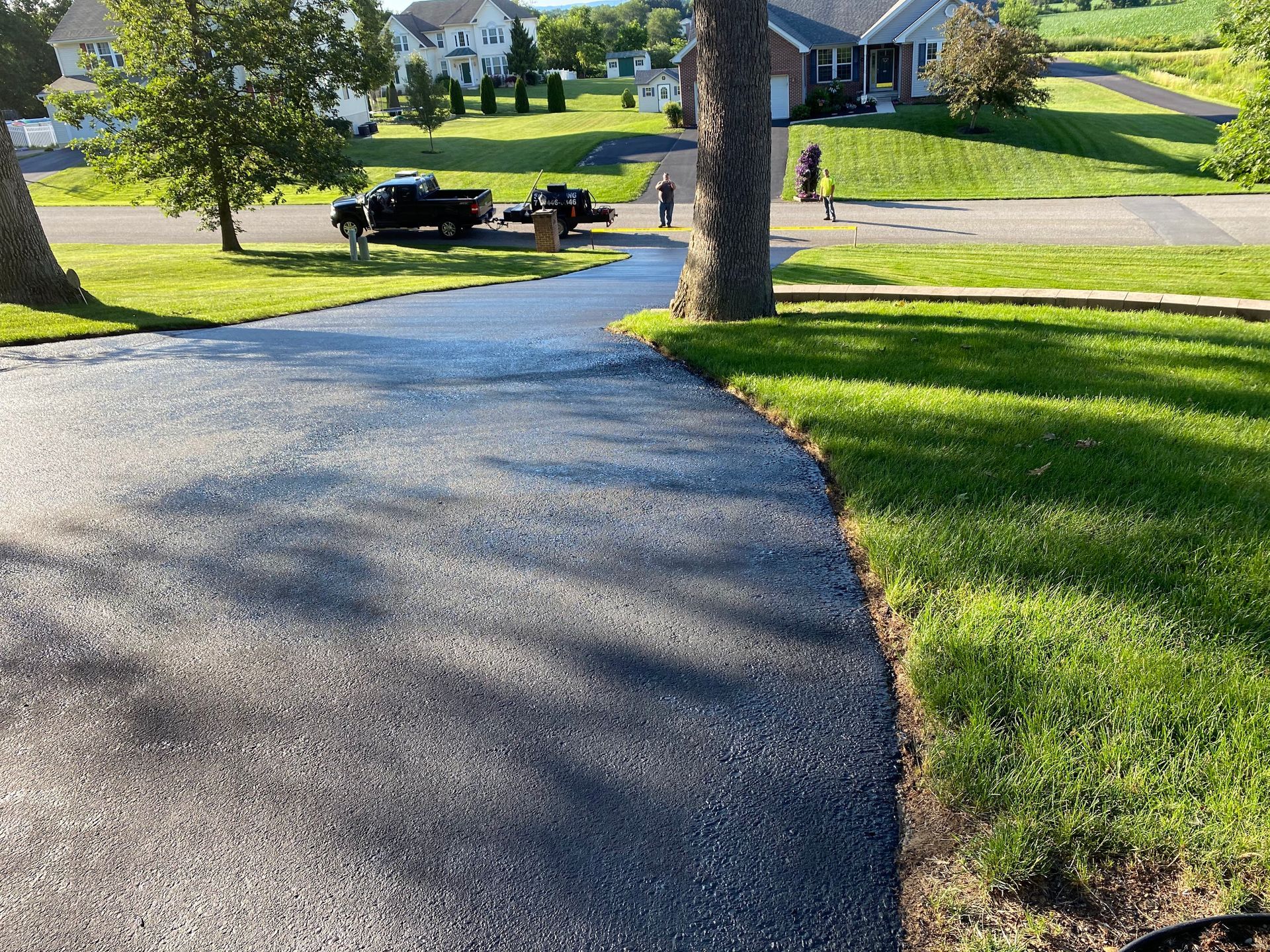 A driveway in a residential neighborhood with a truck parked on the side of it.