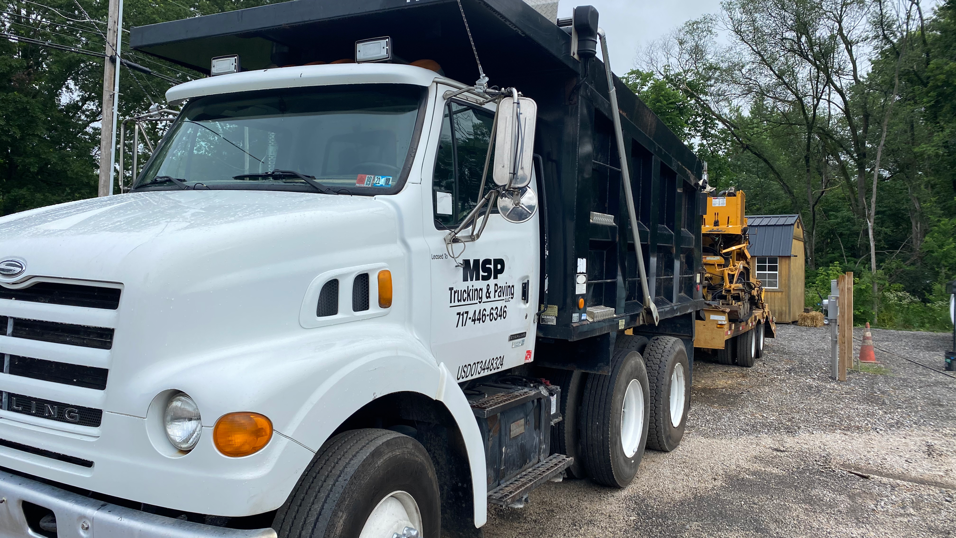 A white dump truck is parked in a gravel lot.