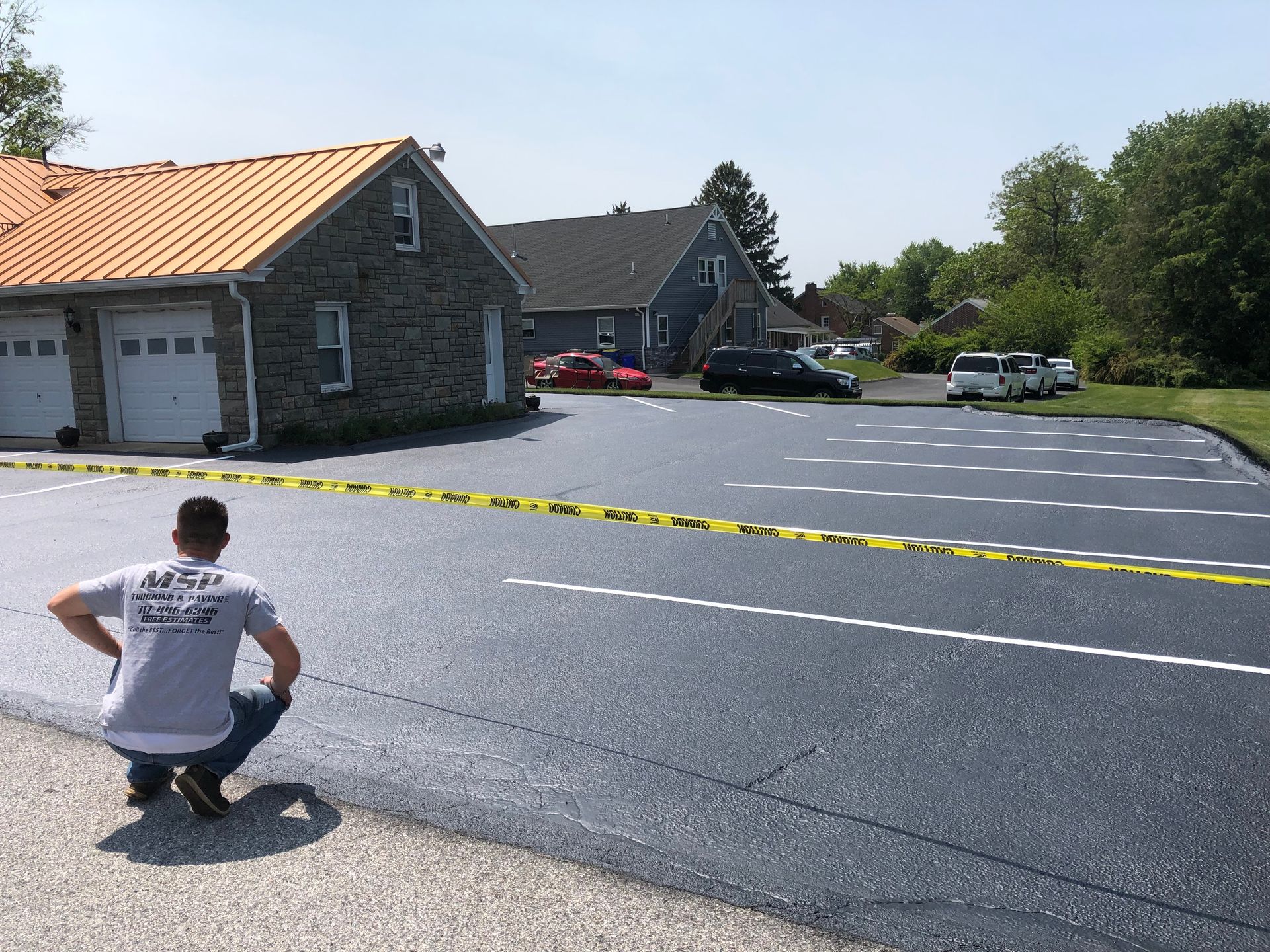 A man is kneeling on the side of a road in front of a house.