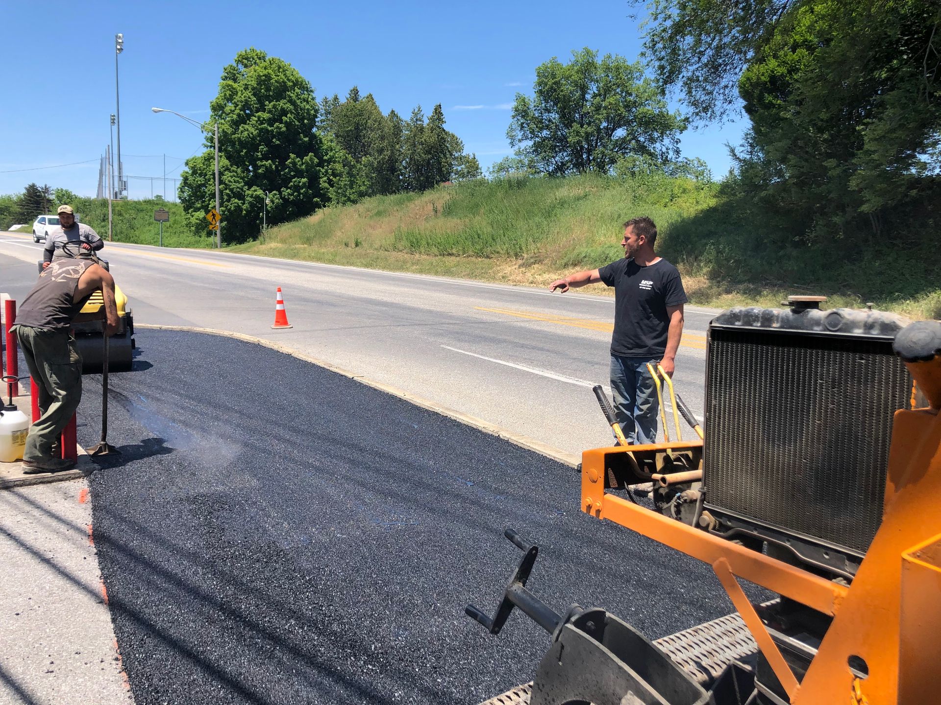 A man is standing next to a machine on the side of a road.