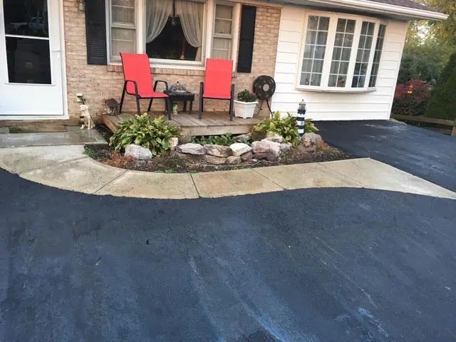 A driveway with two red chairs in front of a house