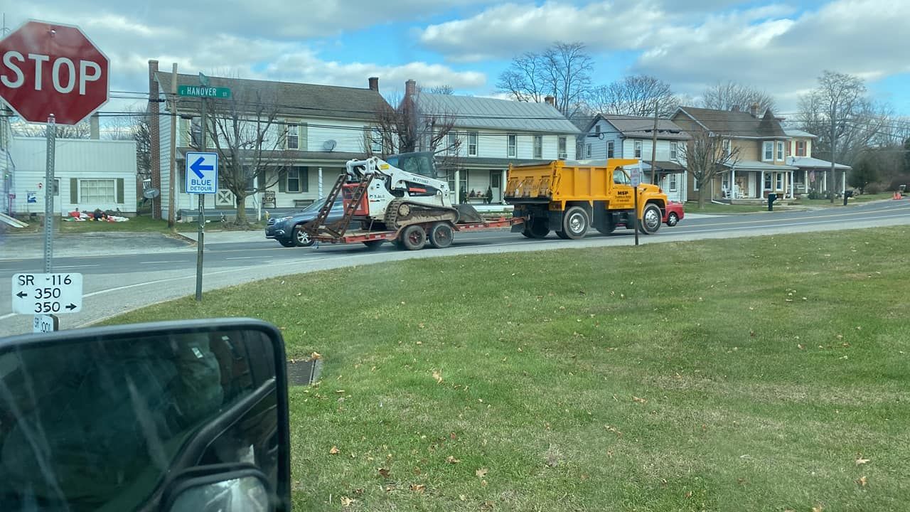 A dump truck is driving down a street next to a stop sign.