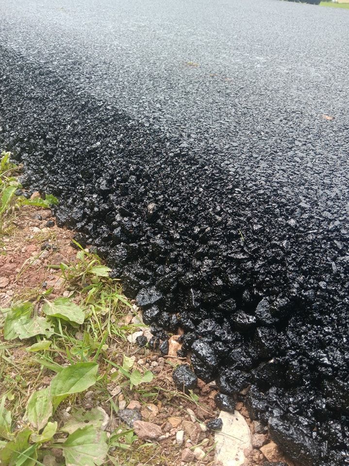 A close up of a pile of black gravel on the side of a road.