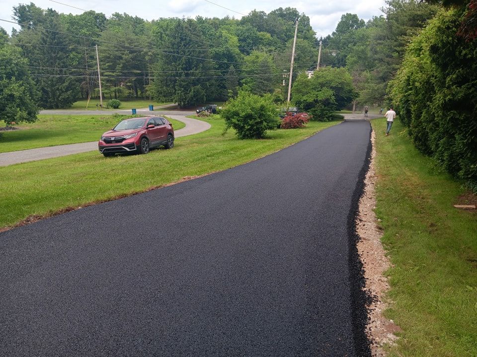 A red car is driving down a newly paved road.