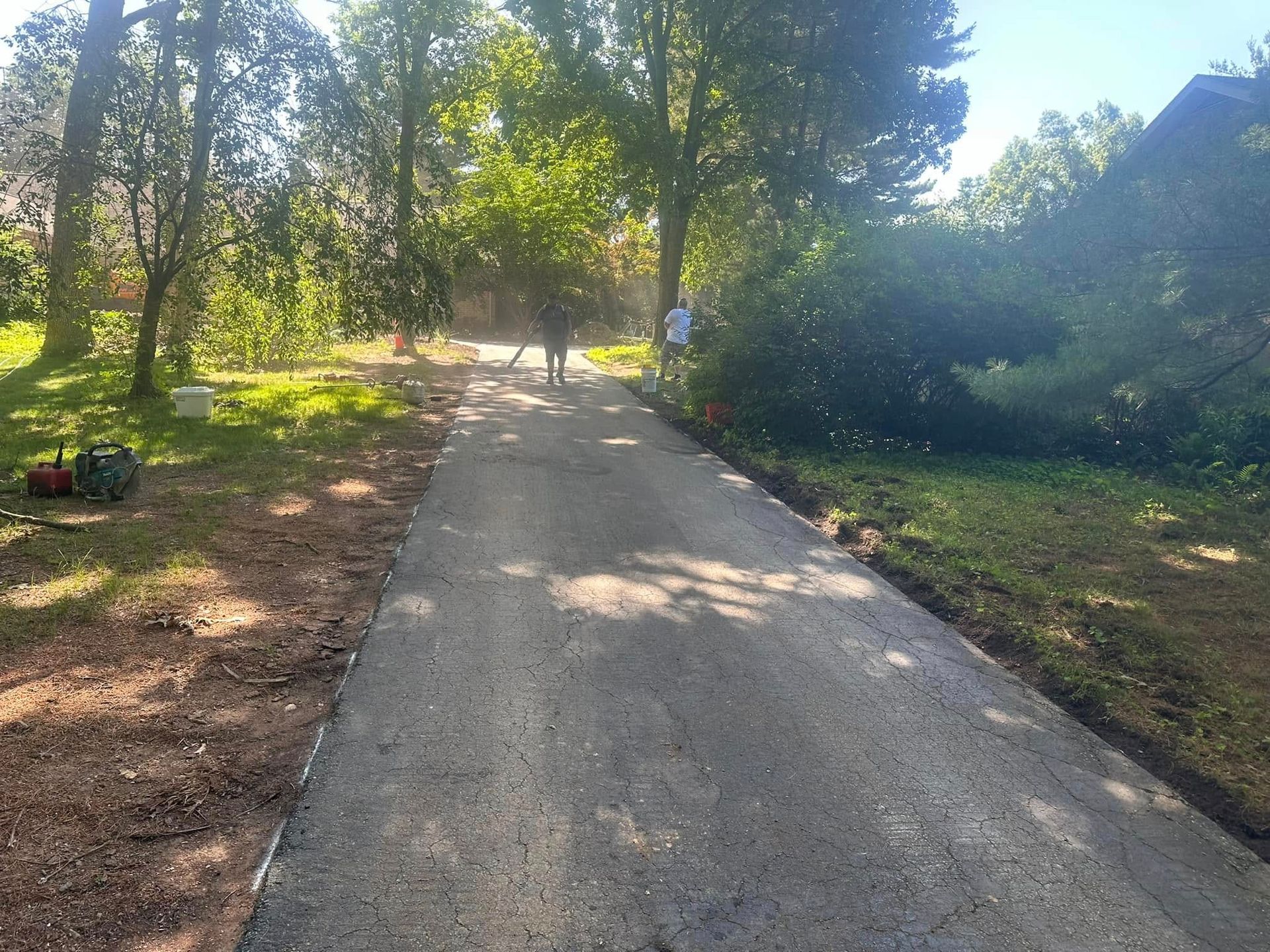 A person is walking down a dirt road surrounded by trees.