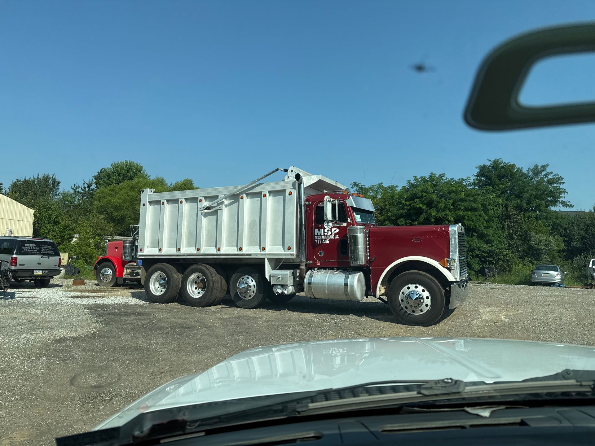 A dump truck is parked in a parking lot next to a house.