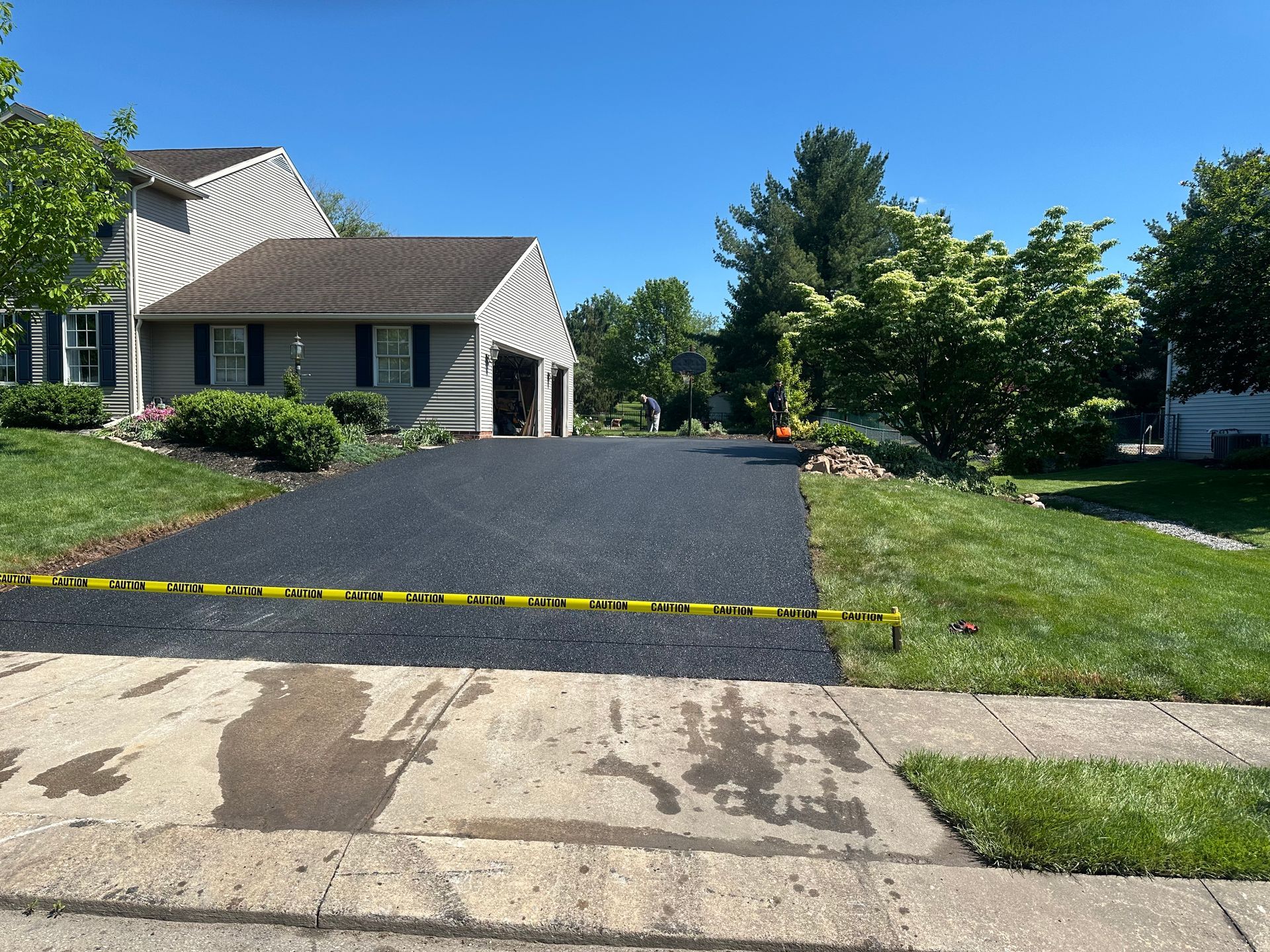 Newly paved asphalt driveway in front of a house, blocked off with caution tape.