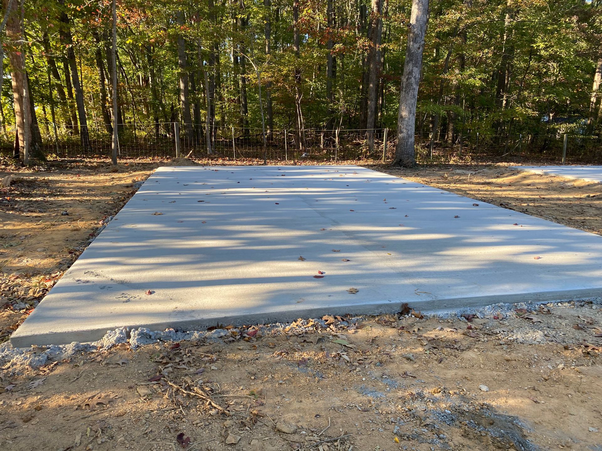A concrete walkway is being built in front of a brick house.