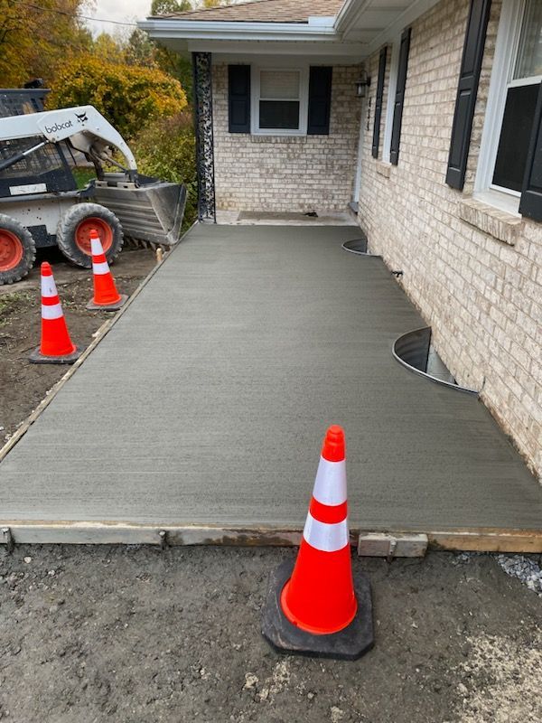 A concrete walkway is being built in front of a brick house.