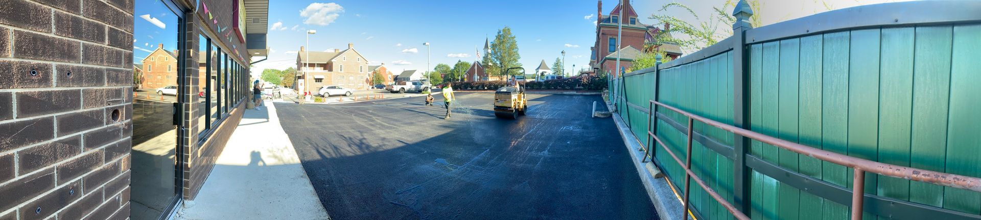 A brick building with a green fence and a river in the background.