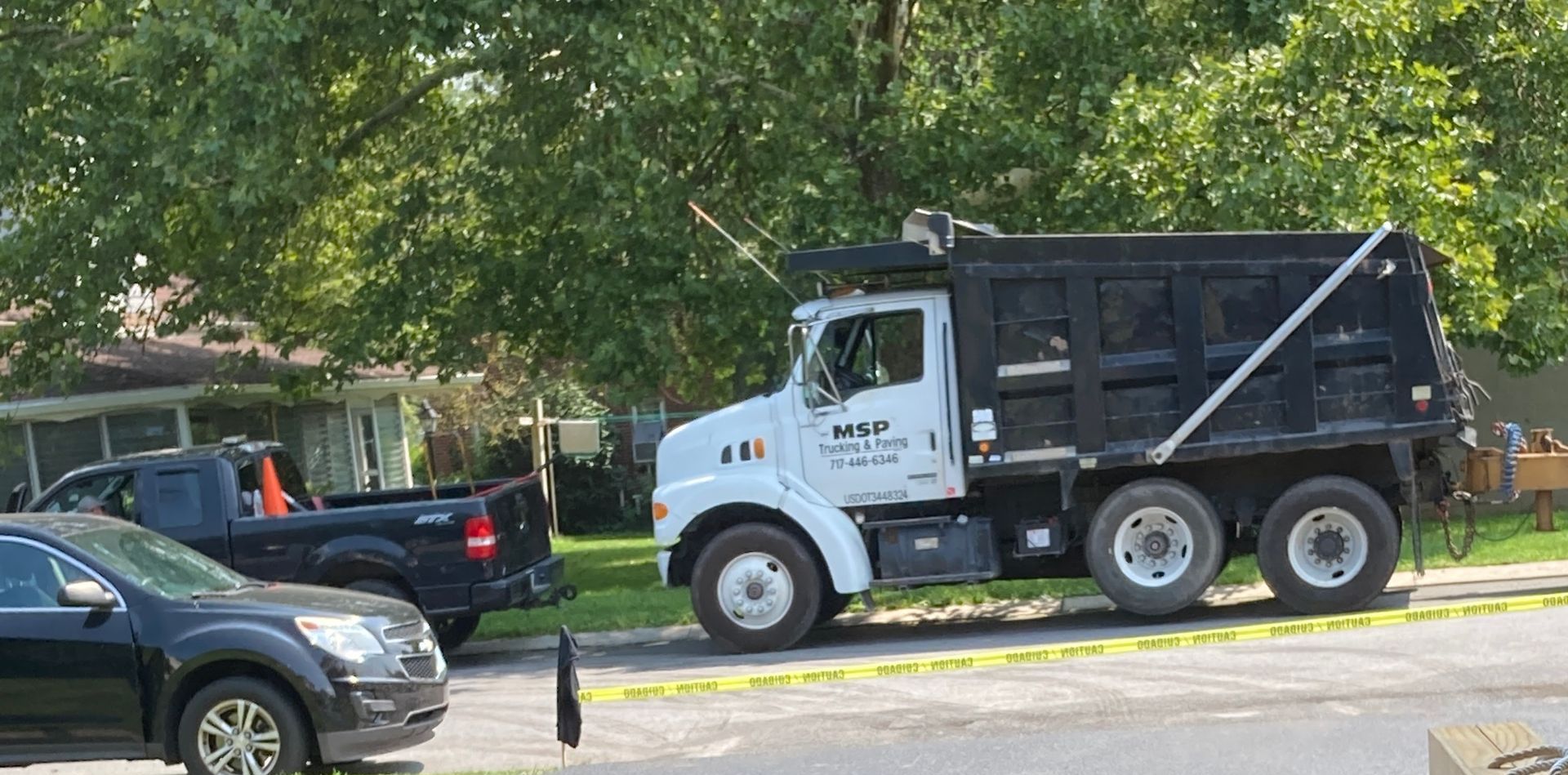 A dump truck is parked in a parking lot next to a house.