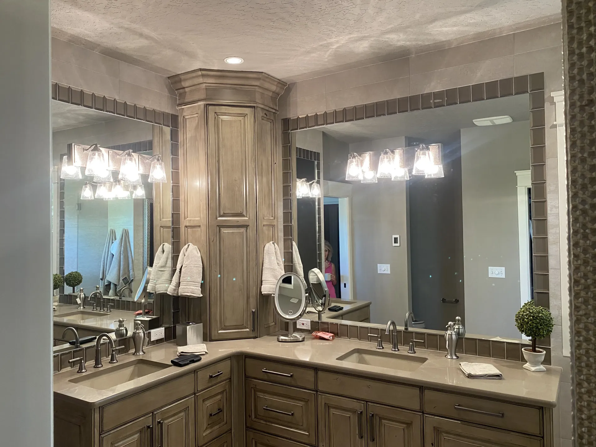 Double vanity bathroom featuring wooden cabinets, dual sinks, large rectangular mirrors, and bright light fixtures.