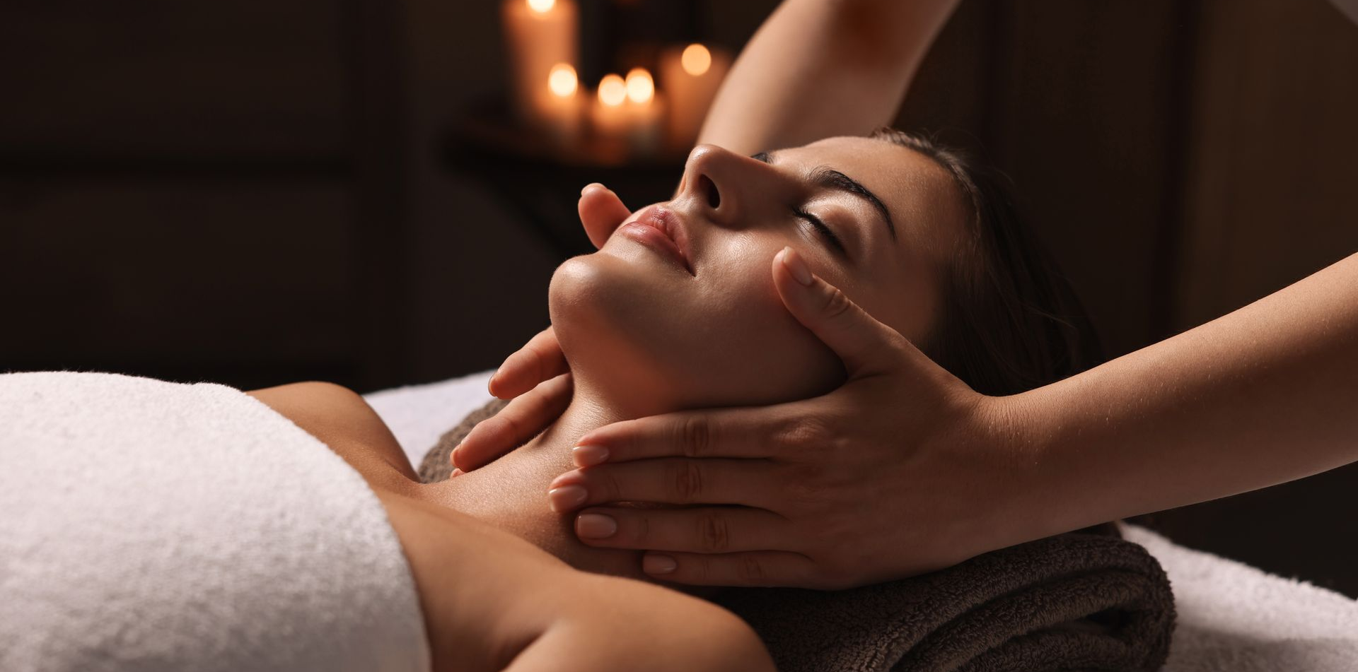 Woman relaxing with a facial mask, lying on a white towel.