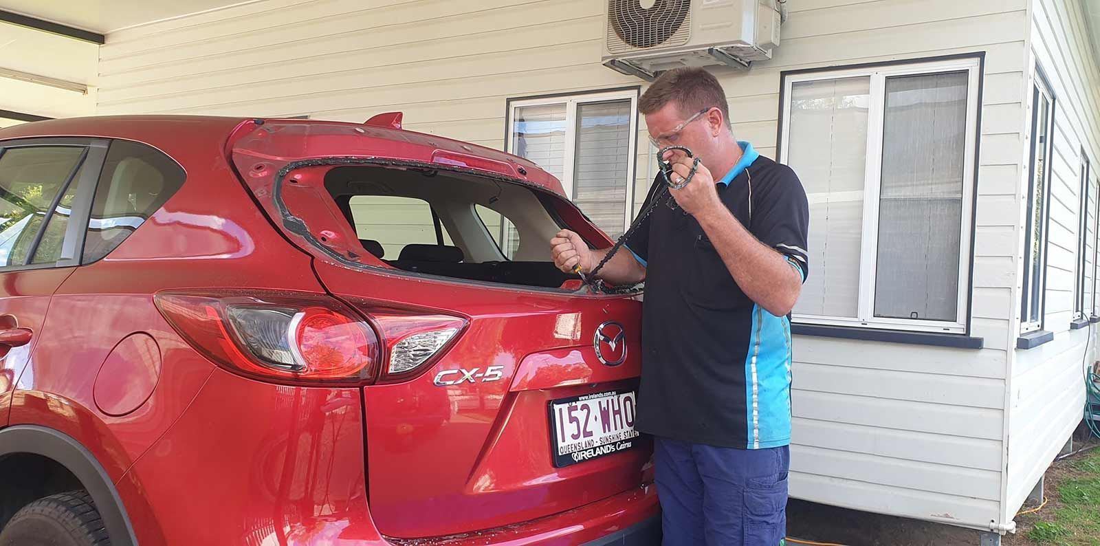 A Man is Replacing A Rear Window on a Car— FNQ Windscreens in Bungalow, QLD