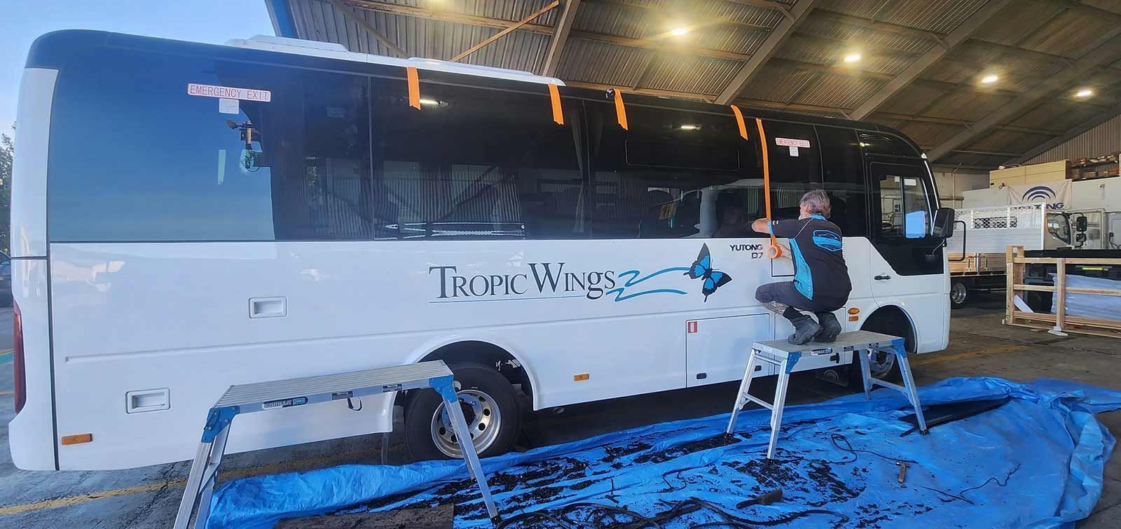 A Man is Repairing a Coach Window — FNQ Windscreens in Bungalow, QLD