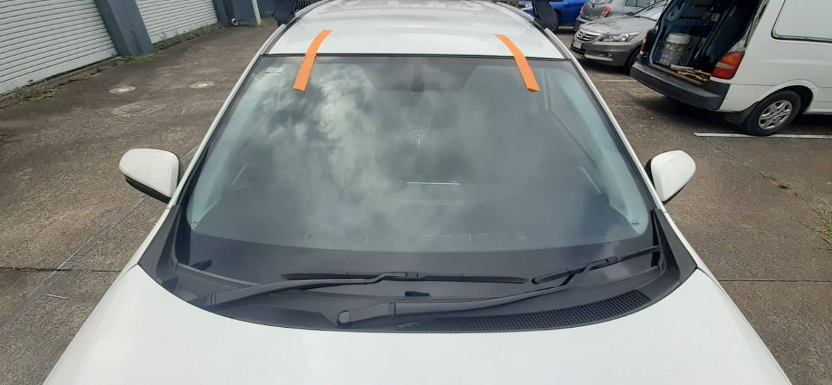 A White Car With a Broken Windshield is Parked in a Parking Lot — FNQ Windscreens in Redlynch, QLD