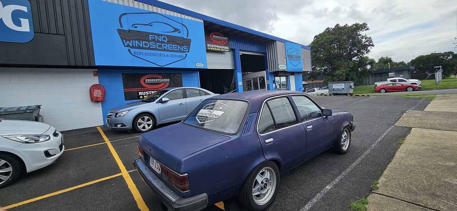A Purple Car is Parked in Front of a Blue Building — FNQ Windscreens in Bungalow, QLD