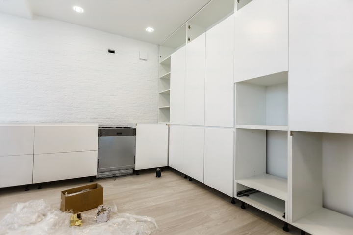 A kitchen under construction with white cabinets and a dishwasher.