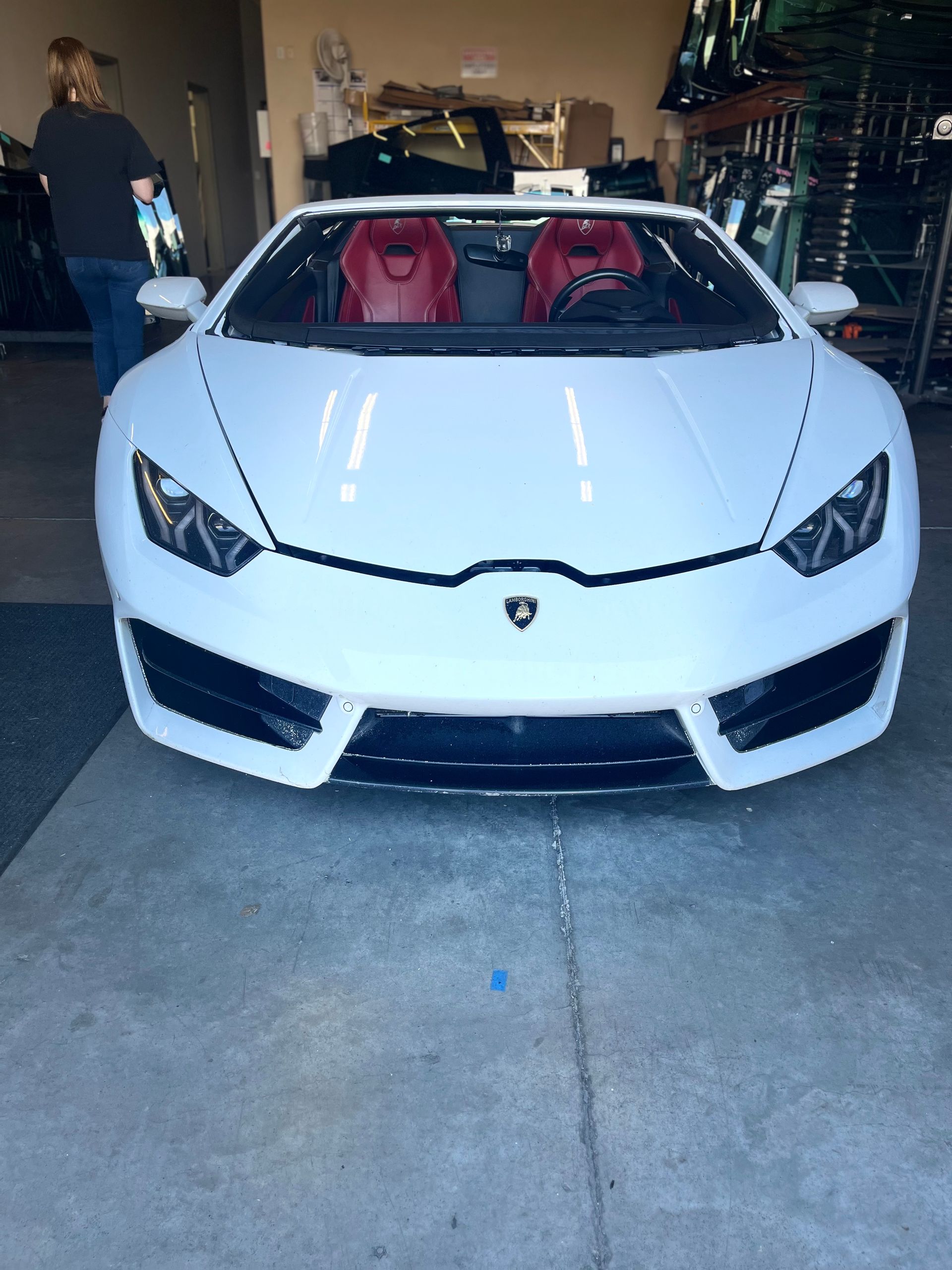 A white sports car with red seats is parked in a garage