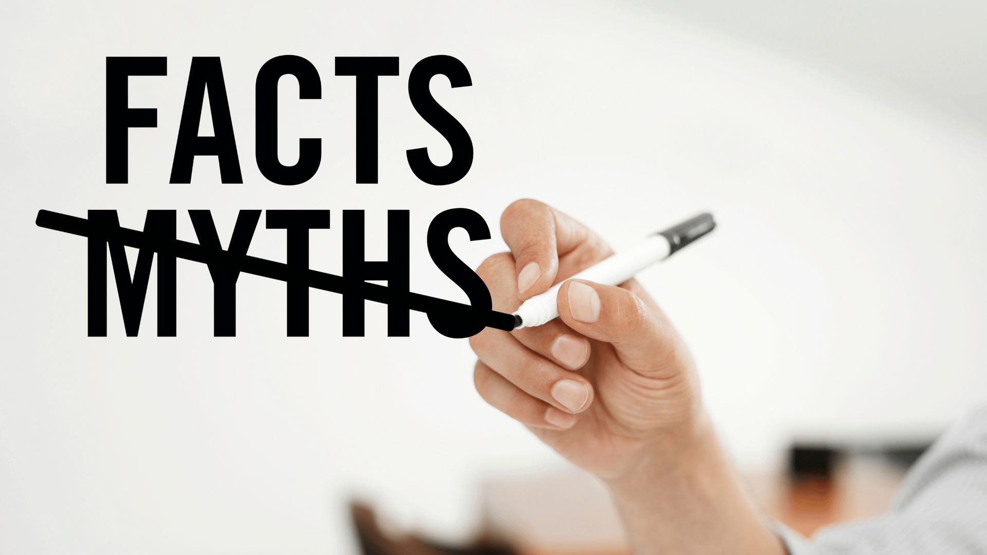 A person is writing the word facts myths with a marker.