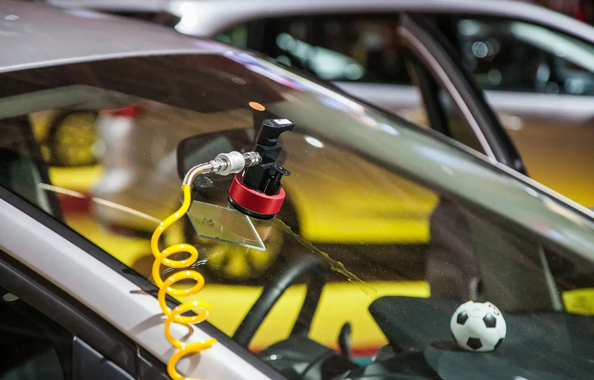 A car windshield is being repaired with a soccer ball on the dashboard.