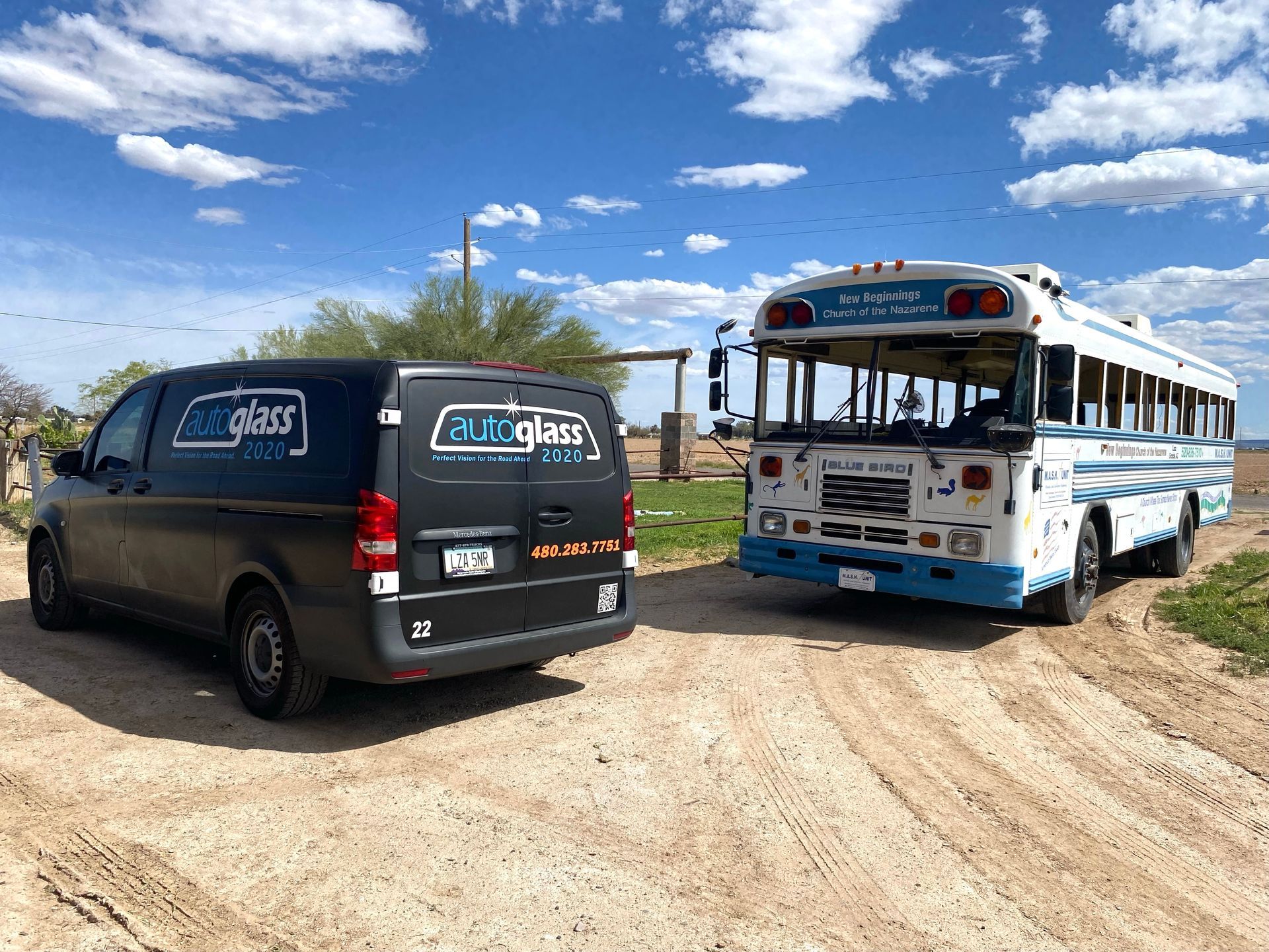 A van and a school bus are parked next to each other on a dirt road.