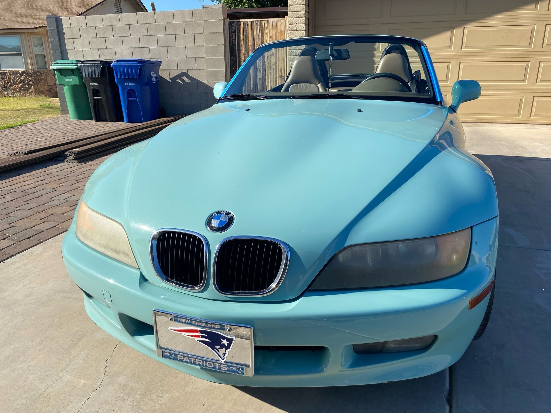 A light blue bmw z3 convertible is parked in a driveway