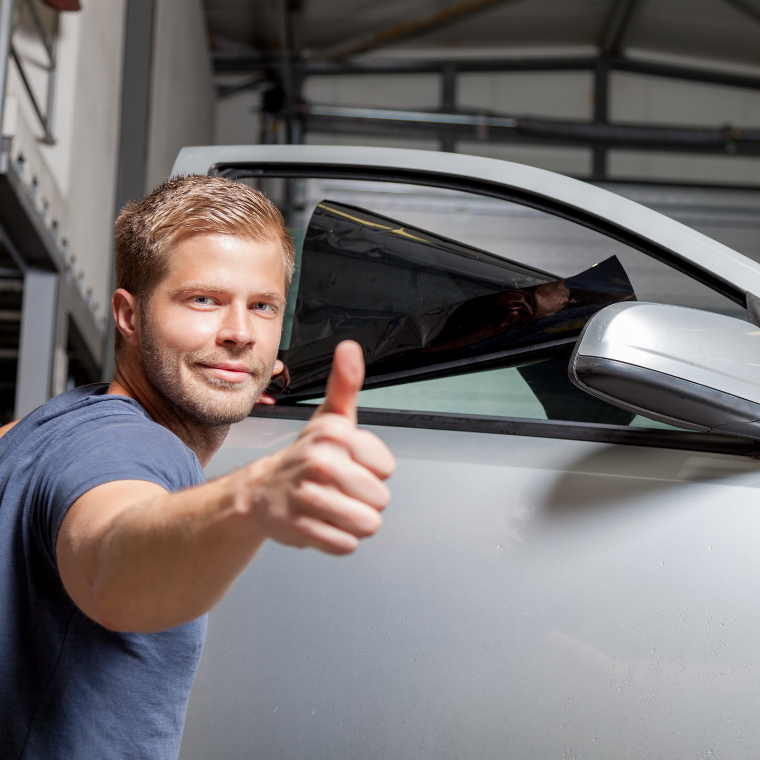 A man giving a thumbs up in front of a car