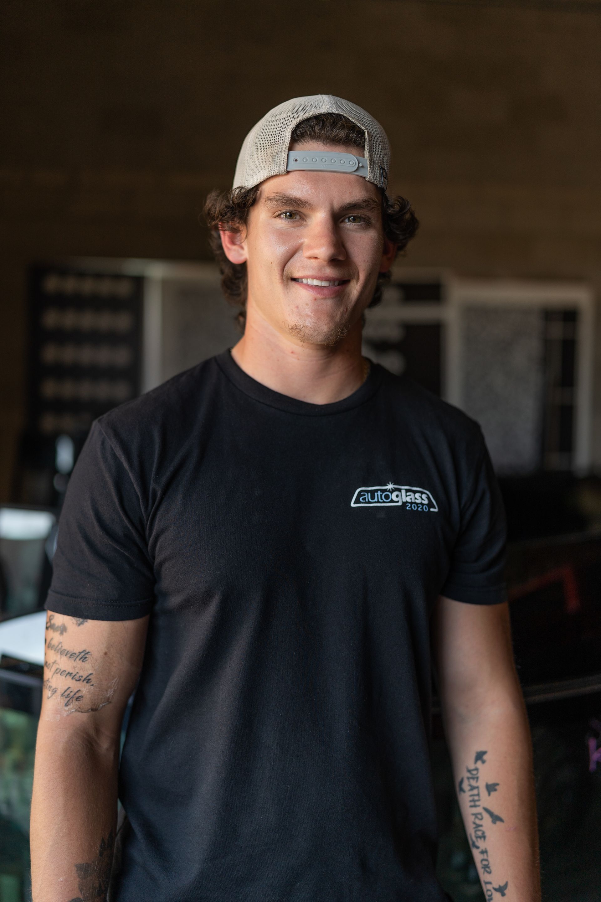 A young man wearing a hat and a black t-shirt is standing in a room.