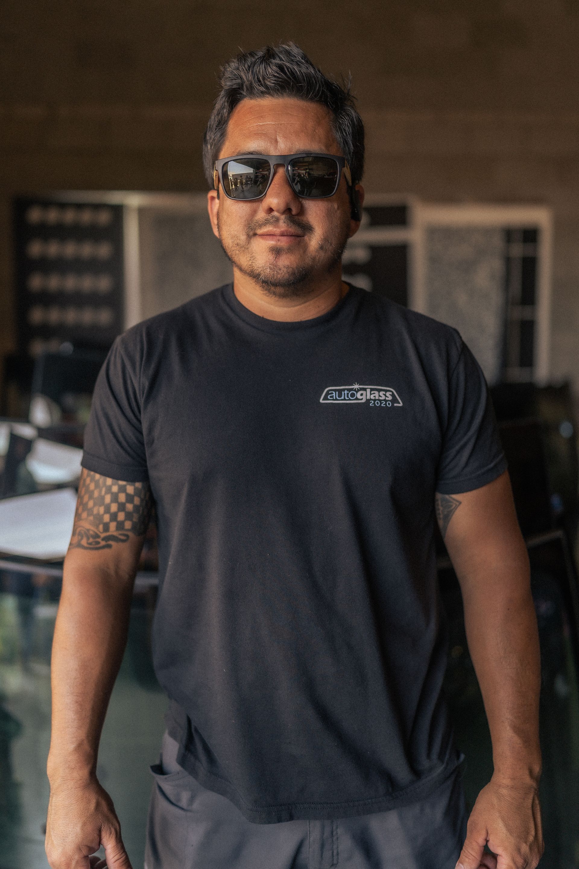 A man wearing sunglasses and a black t-shirt is standing in a room.