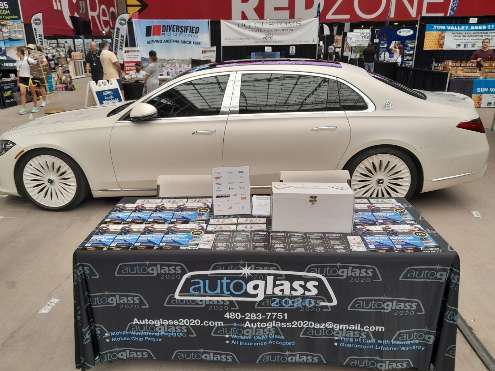 A white car is parked next to a table that says autoglass