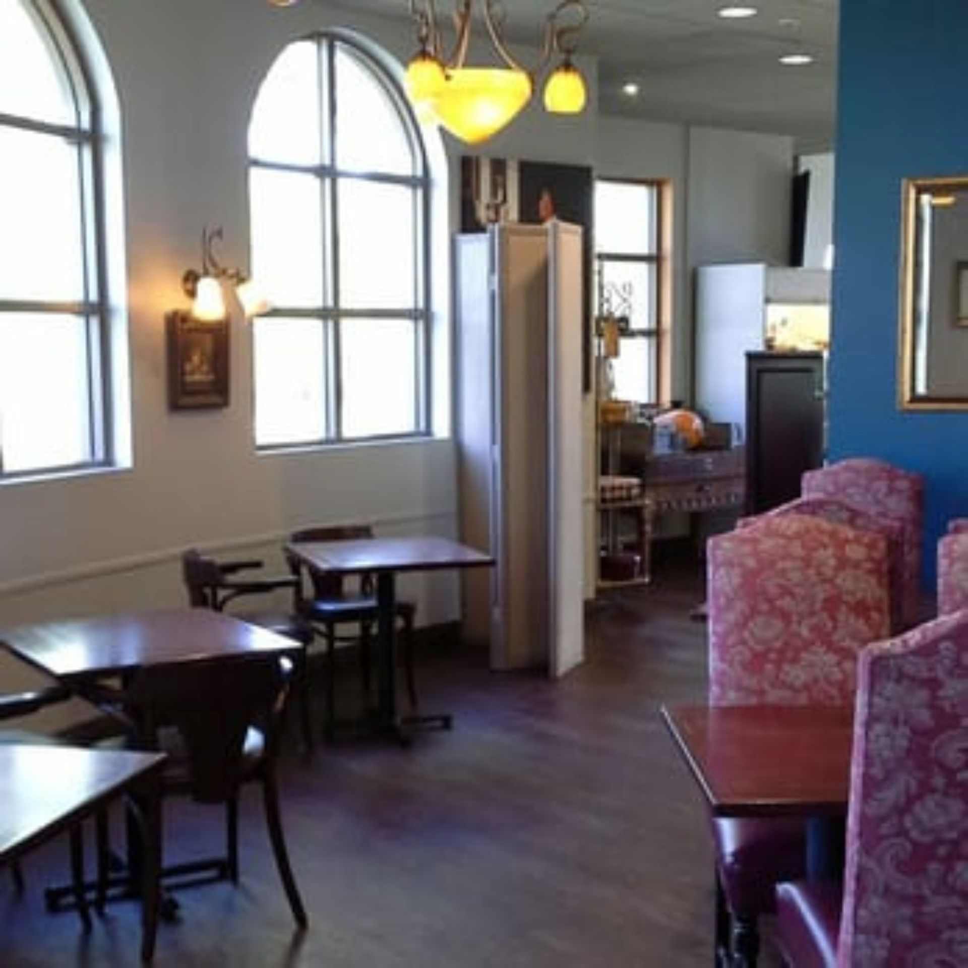 The right color - Restaurant interior with tables, chairs, arched windows, and decorative lighting.