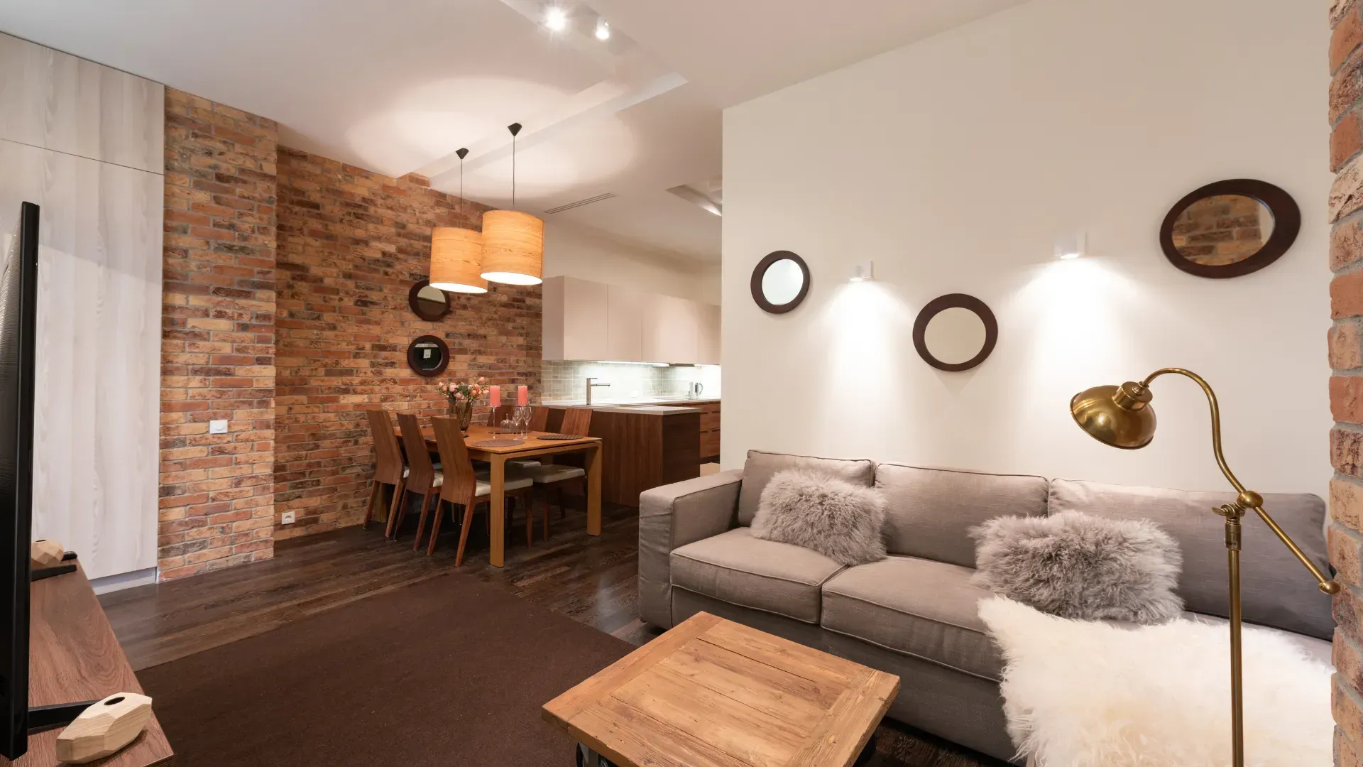 The right color - Cozy living room with brick accent wall, sofa, dining table, mirrors, and floor lamp.