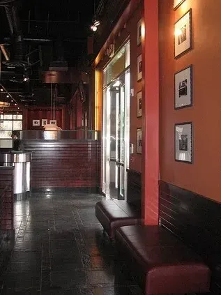The right color - Interior of a building with red and dark wood accents, a bench, and framed photos on an orange wall.