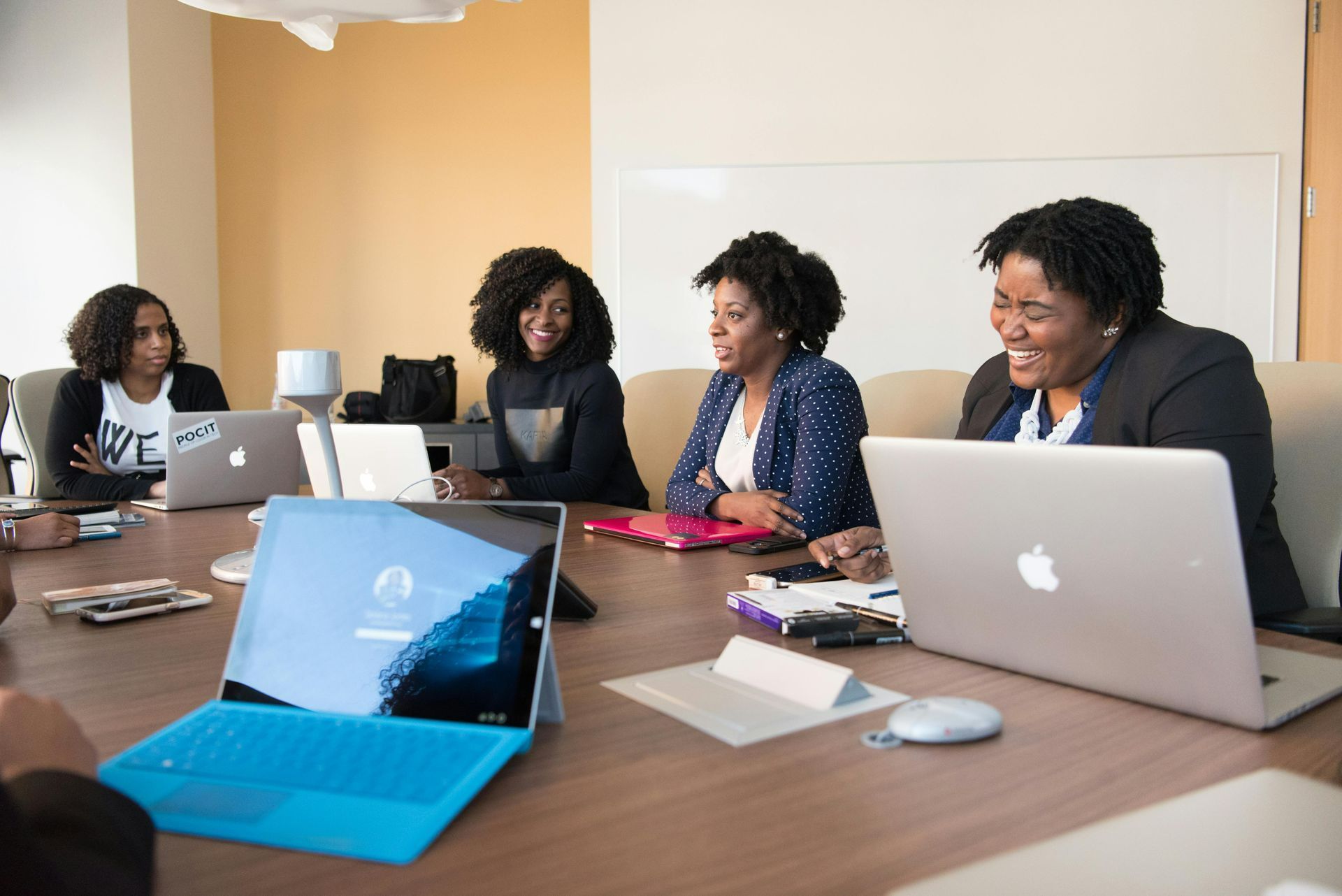 A group of people are sitting around a table with laptops.