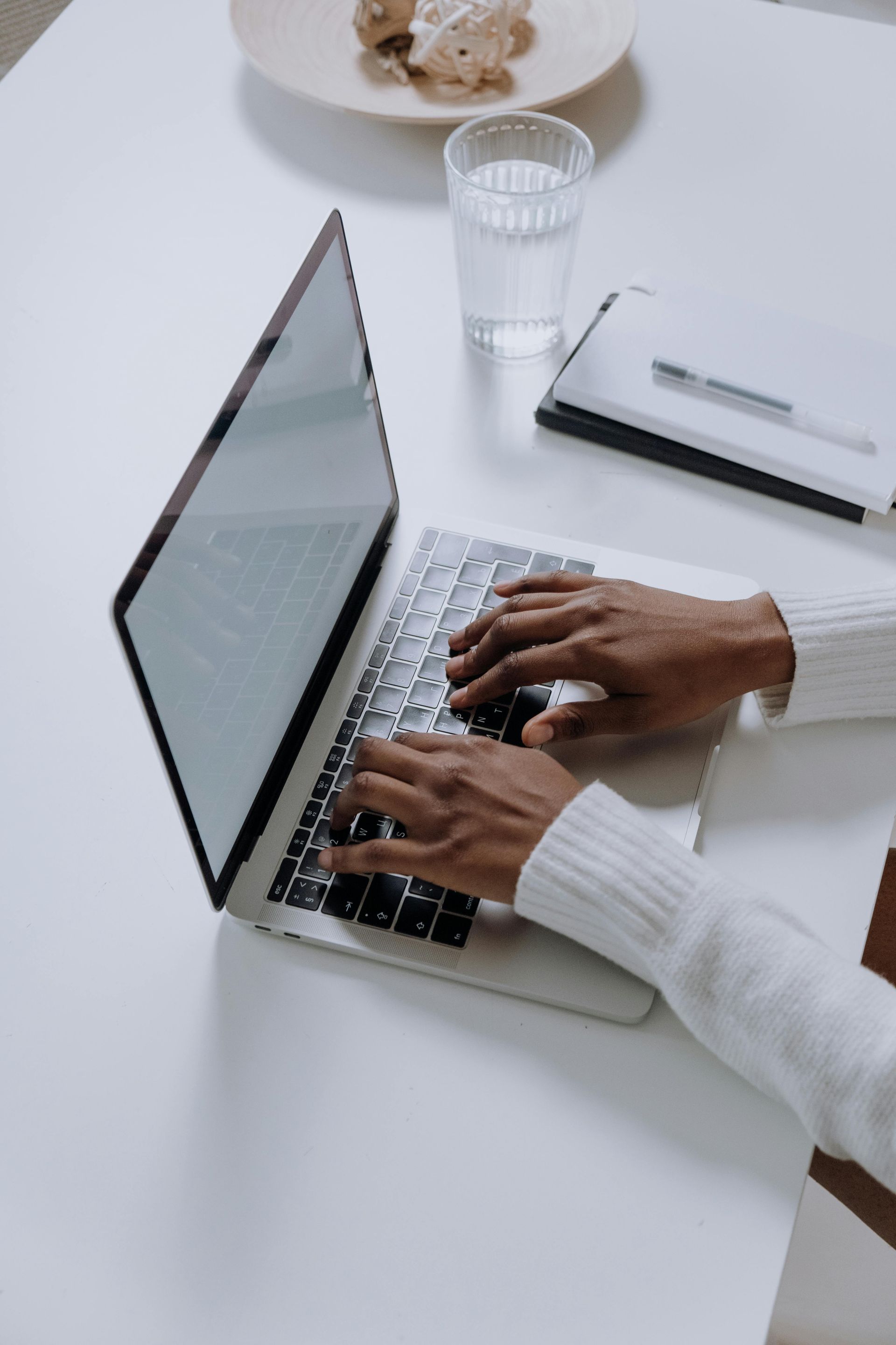 A person is typing on a laptop computer at a table.