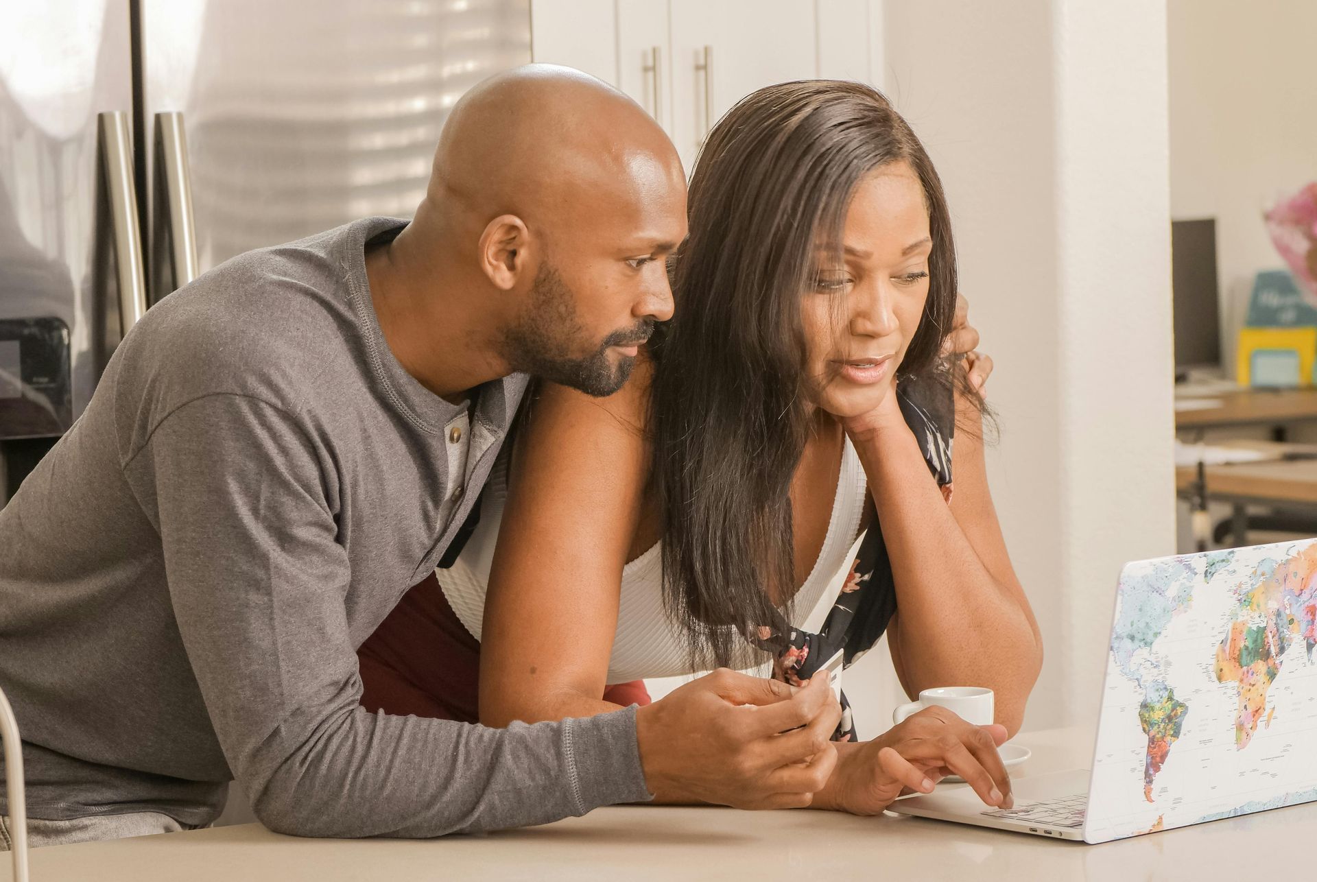 A man and a woman are looking at a laptop computer.
