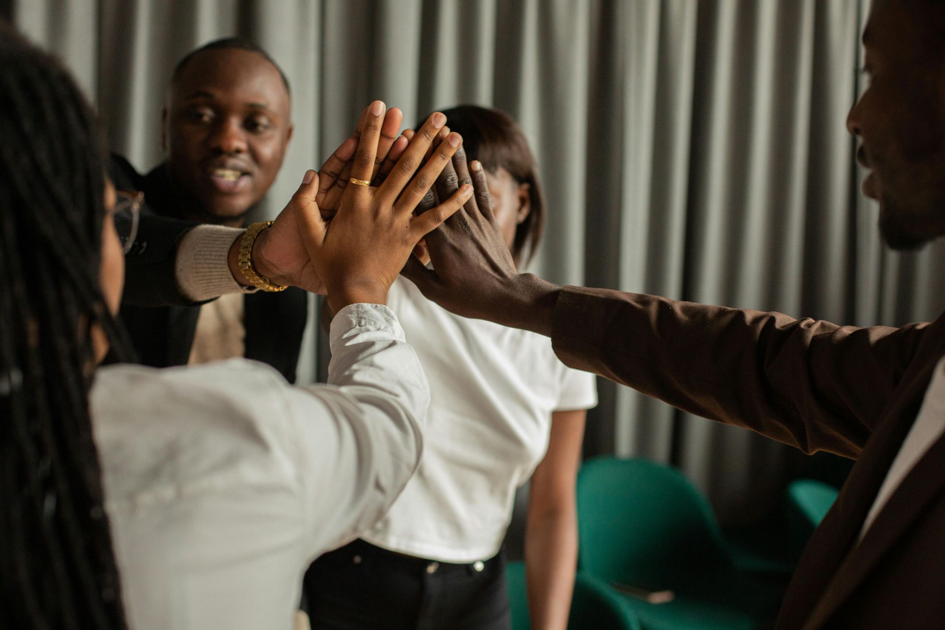A group of people are sitting around a wooden table shaking hands.
