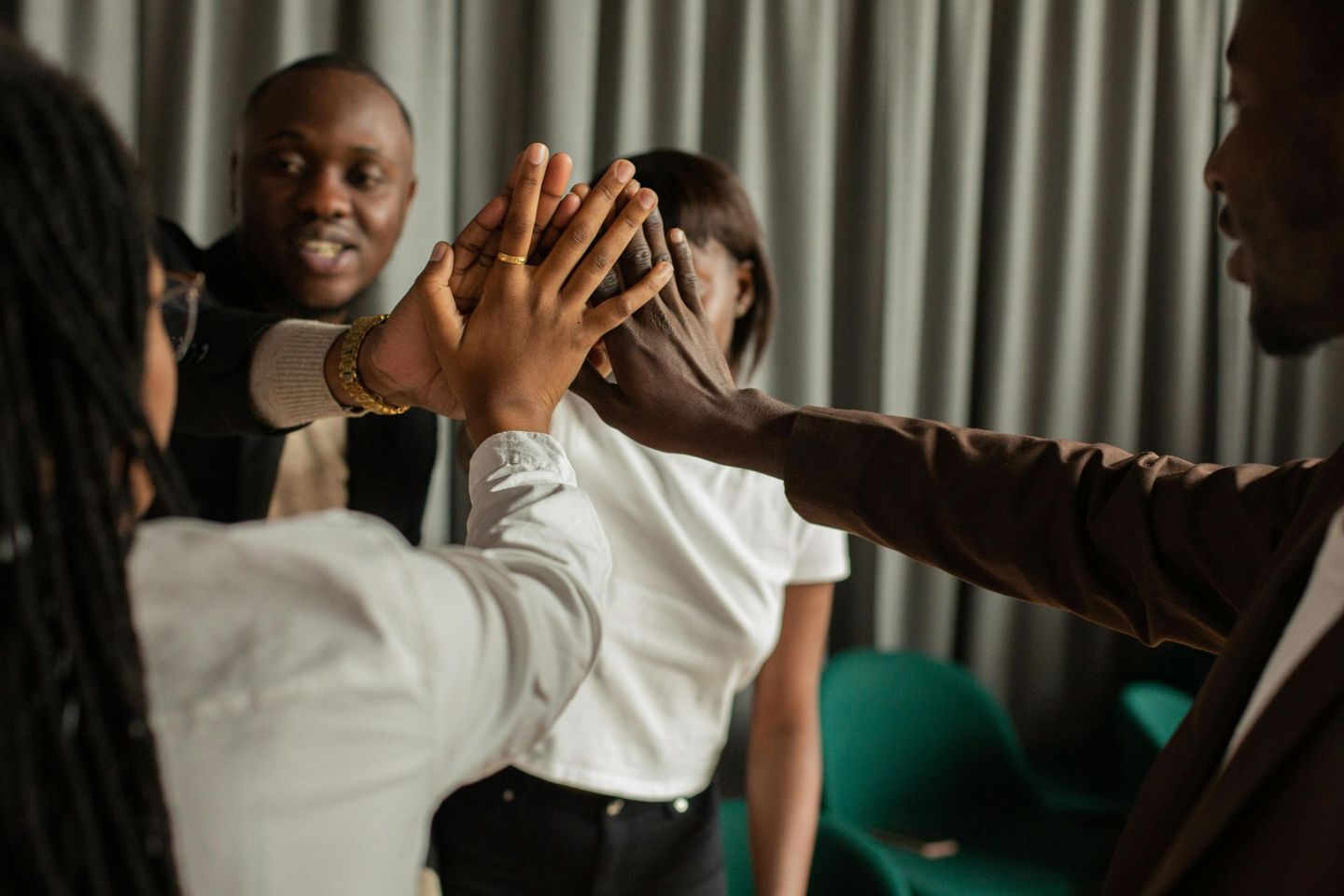 A group of people are sitting around a wooden table shaking hands.