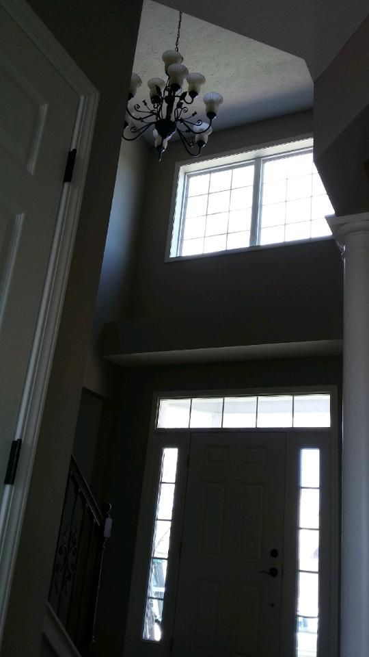 Entryway with chandelier, tall windows, and front door with sidelights.