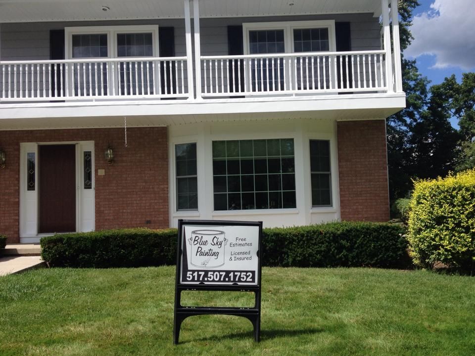 Two-story brick home with white trim and a sign for 