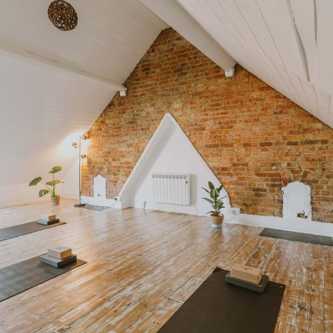 A loft studio with yoga mats and yoga blocks laid out ready for a class